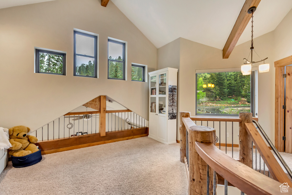Hall with carpet floors, an upstairs landing, beamed ceiling, and high vaulted ceiling