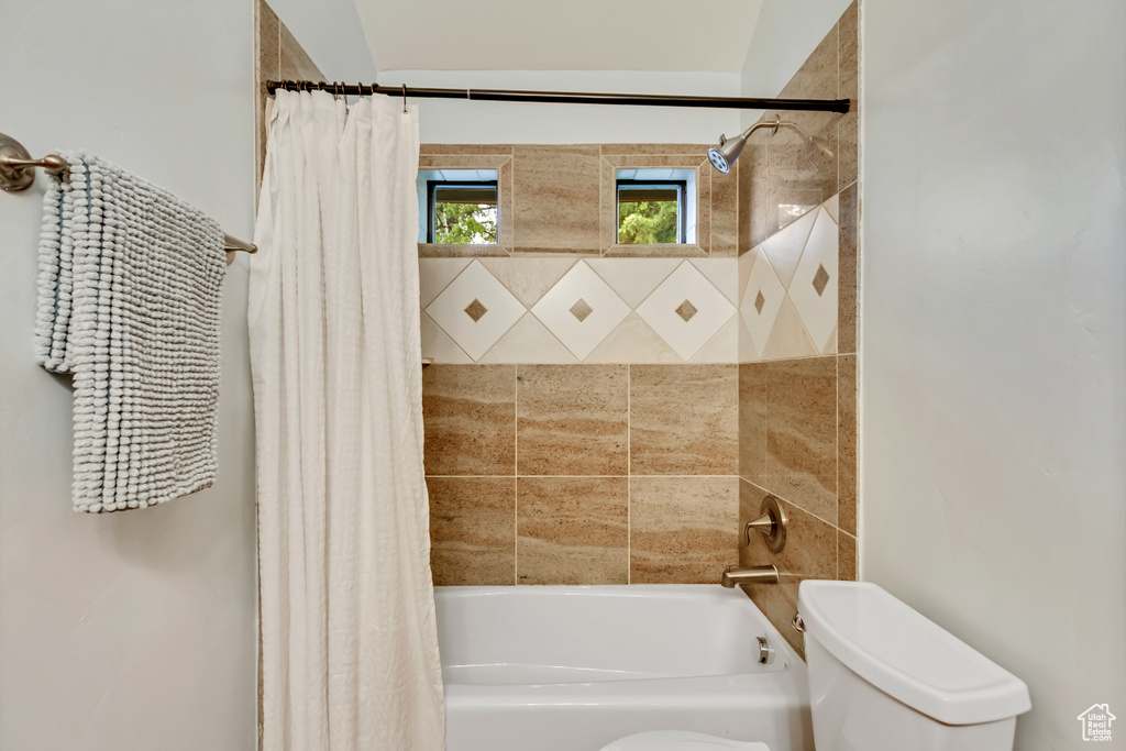 Bathroom featuring shower / bathtub combination with curtain and toilet