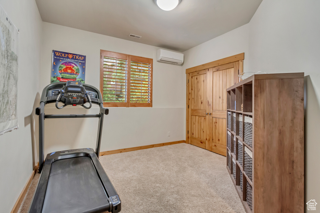 Workout room featuring an AC wall unit, carpet, and baseboards