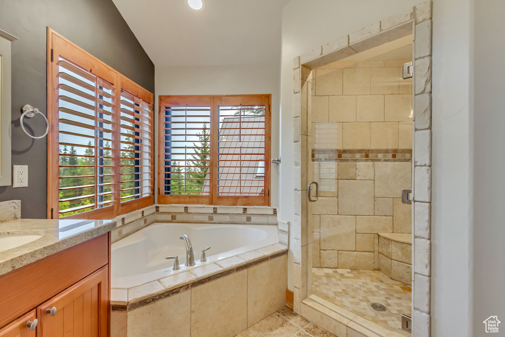 Bathroom featuring a garden tub, a stall shower, and vanity