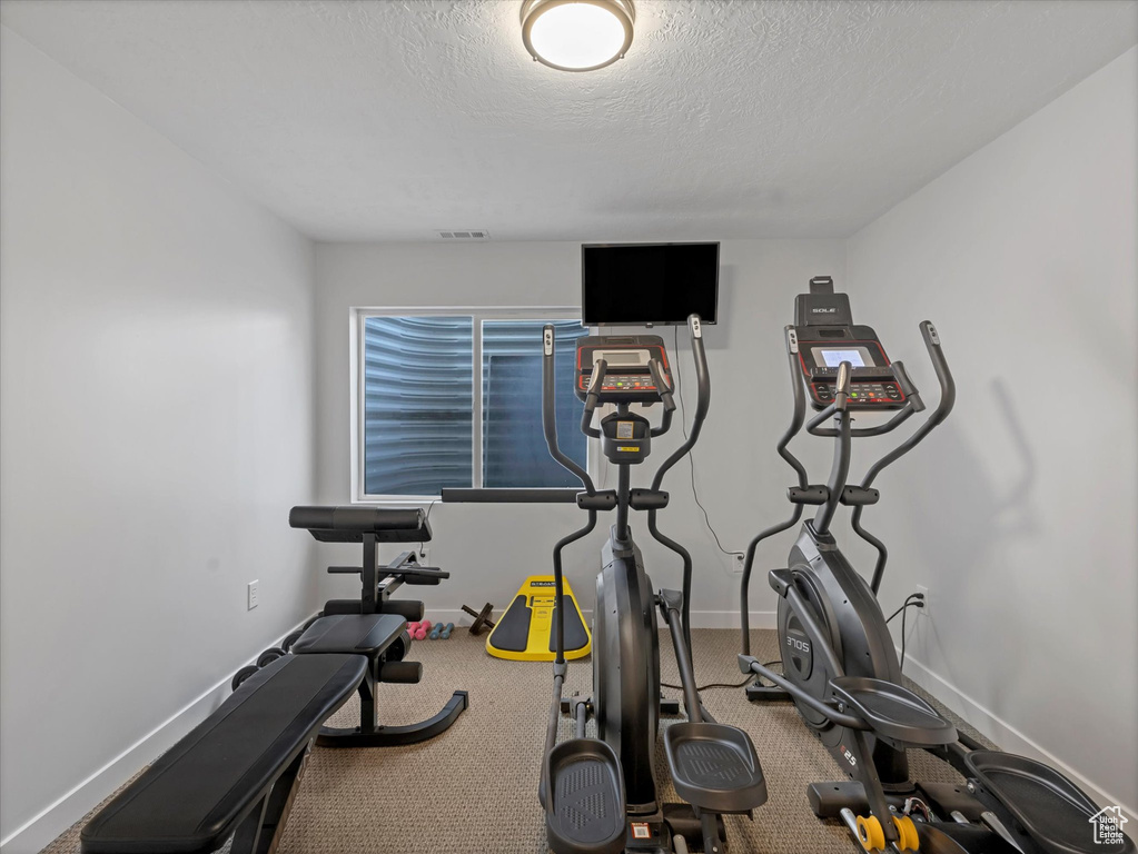 Exercise area featuring baseboards and a textured ceiling