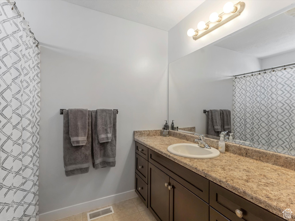 Bathroom with vanity, tile patterned floors, and baseboards