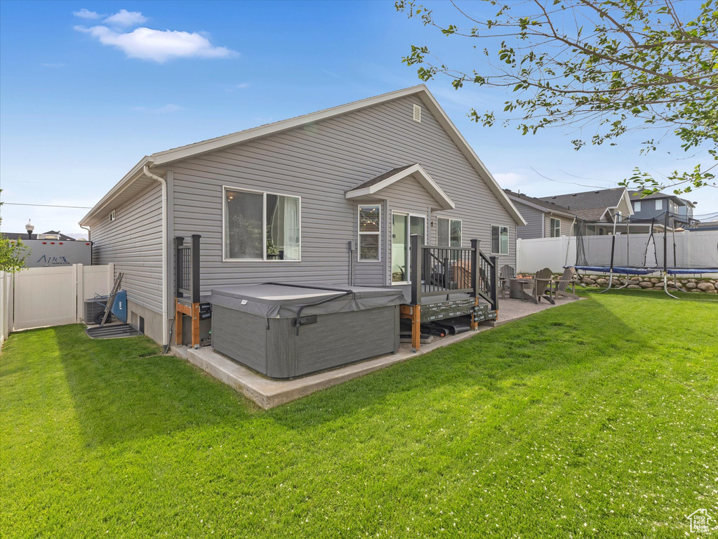 Rear view of property with a trampoline and a hot tub