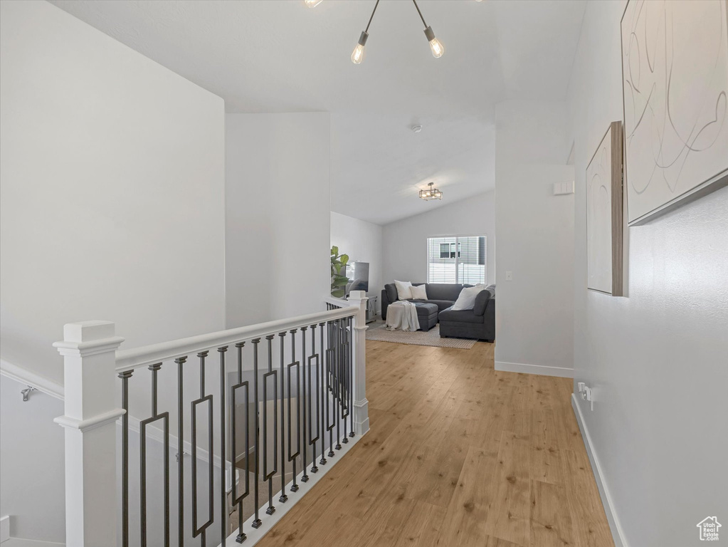 Hallway featuring an upstairs landing, wood finished floors, baseboards, and lofted ceiling