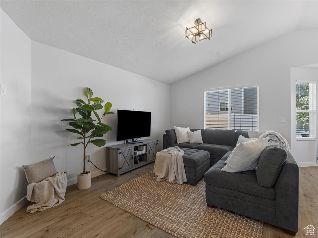 Living room with vaulted ceiling, wood finished floors, and baseboards