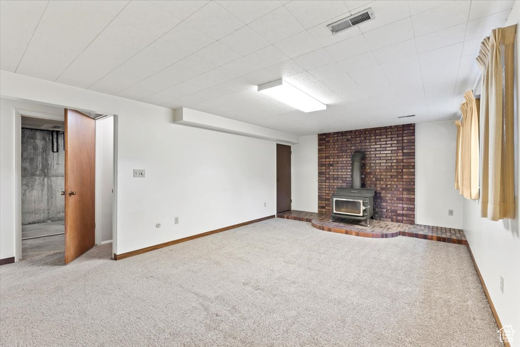Unfurnished living room with a wood stove, carpet floors, and baseboards