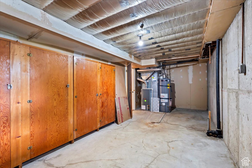Unfinished below grade area featuring secured water heater and heating unit