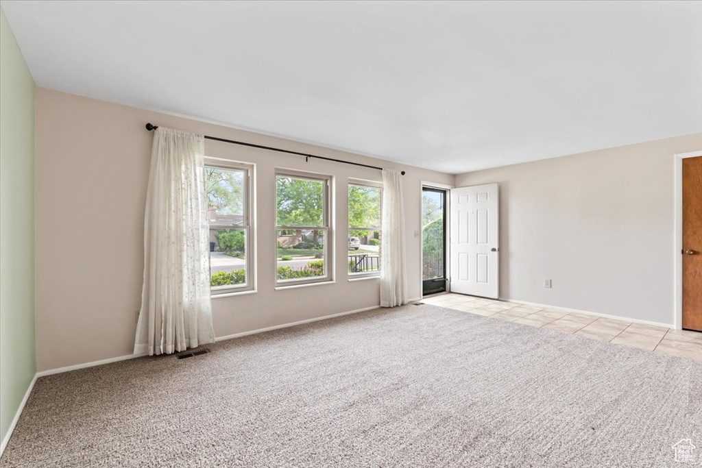 Empty room featuring light carpet, baseboards, and light tile patterned flooring