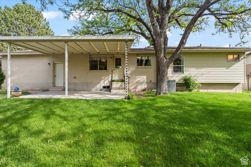 Rear view of house featuring entry steps, a lawn, a patio area, and brick siding