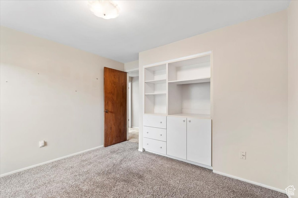 Unfurnished bedroom with light carpet, baseboards, and a closet