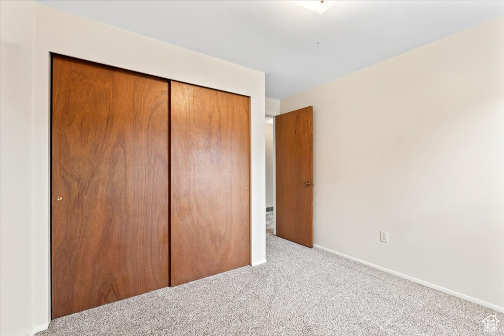 Unfurnished bedroom with carpet flooring, a closet, and baseboards