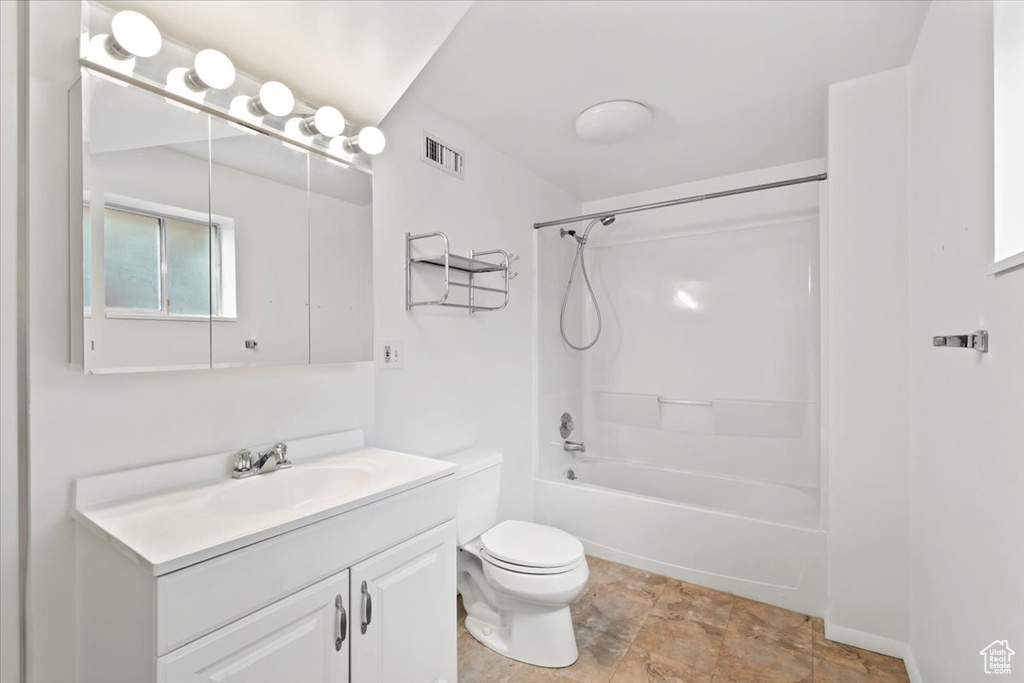 Full bath featuring toilet, vanity, shower / bath combination, and stone finish flooring