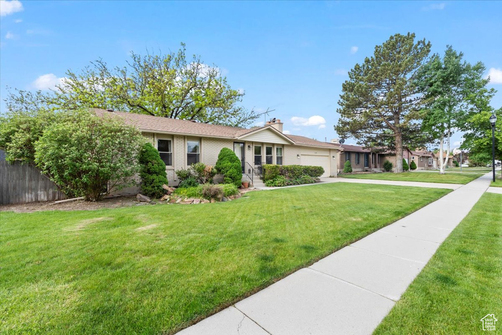 Ranch-style house with a garage, concrete driveway, brick siding, and a chimney