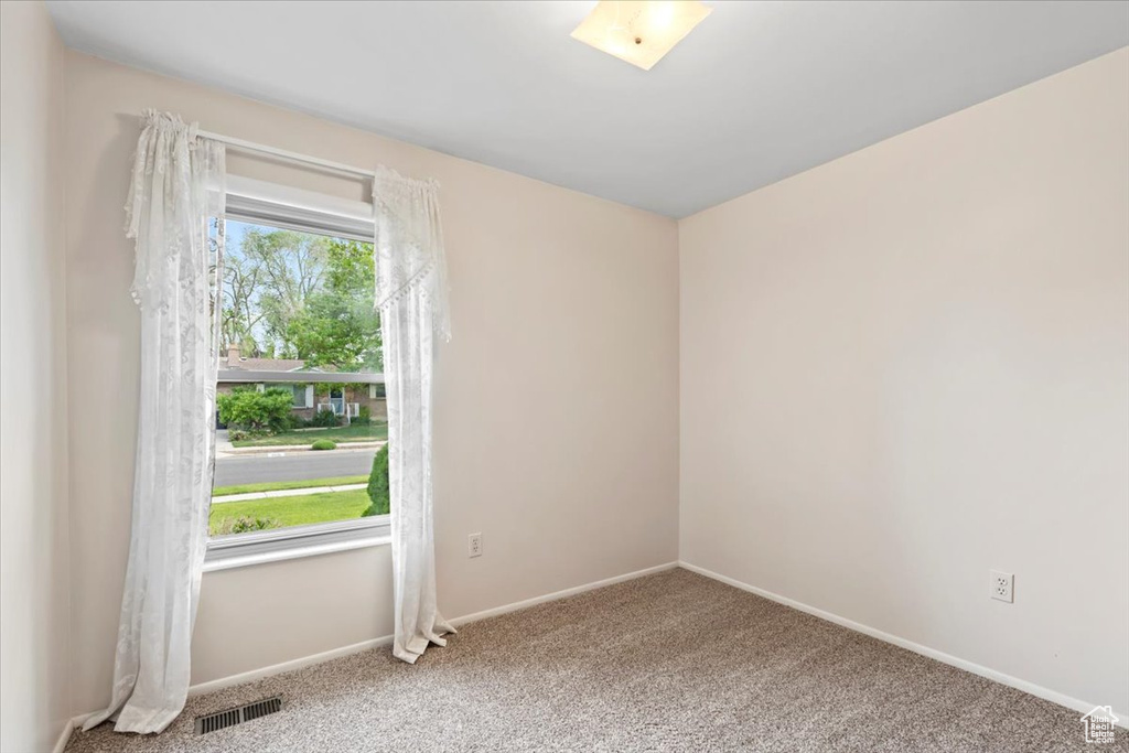 Carpeted spare room featuring baseboards