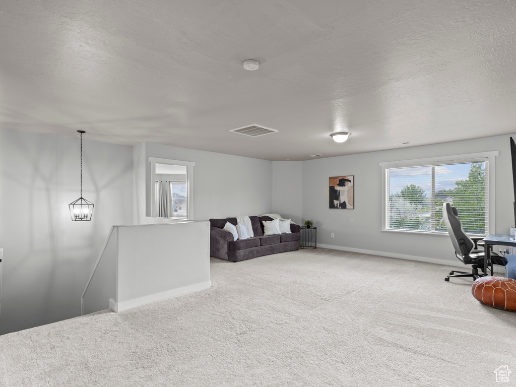 Living area featuring an upstairs landing, carpet flooring, a desk, baseboards, and a textured ceiling