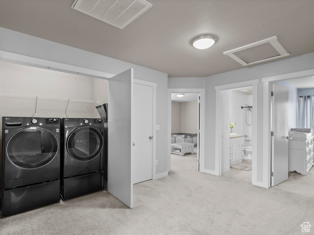 Clothes washing area featuring washer and clothes dryer, attic access, carpet flooring, and baseboards