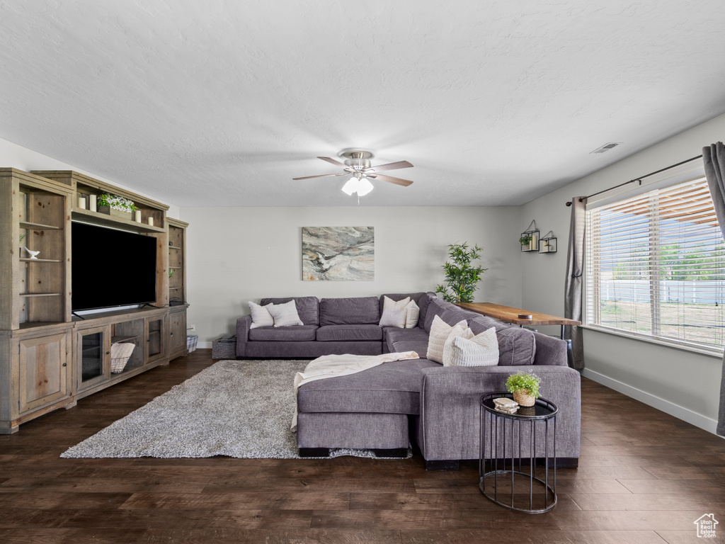 Living room featuring dark wood-style floors, ceiling fan, and baseboards