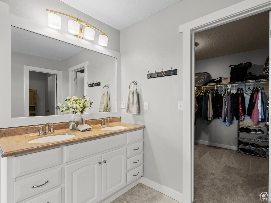 Bathroom with double vanity, a spacious closet, and baseboards