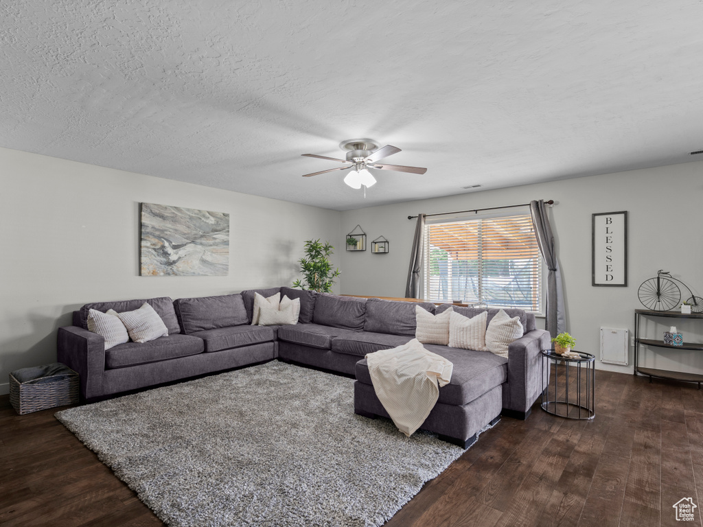 Living area featuring dark wood-style flooring and ceiling fan