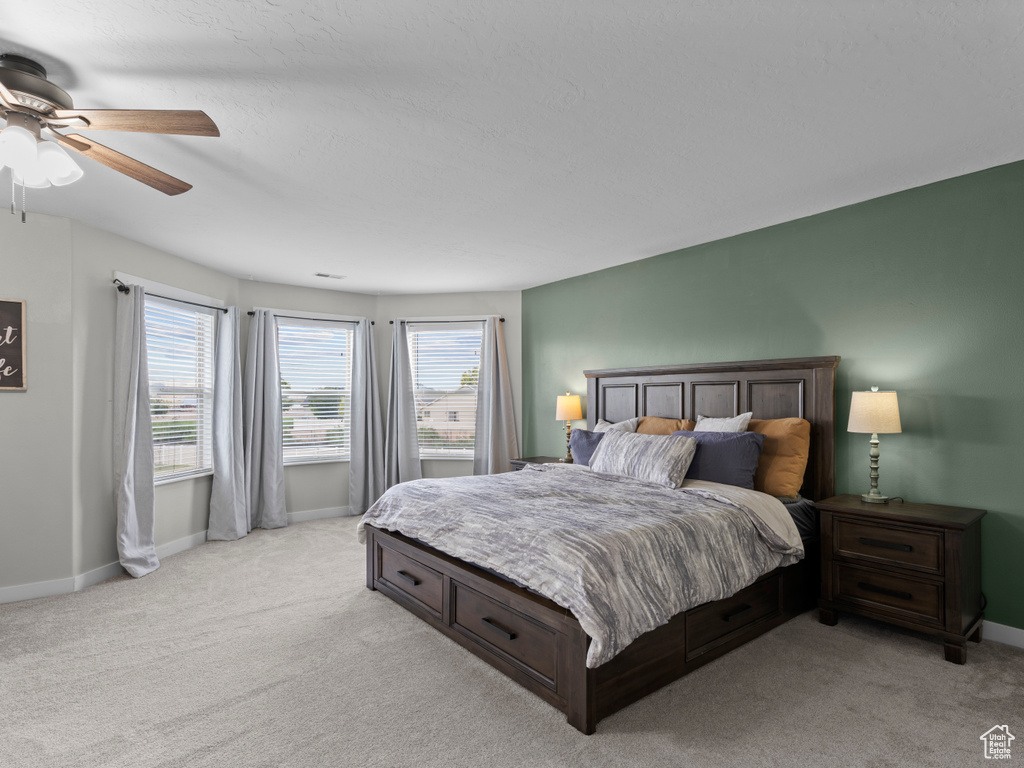 Bedroom featuring light colored carpet, baseboards, and ceiling fan