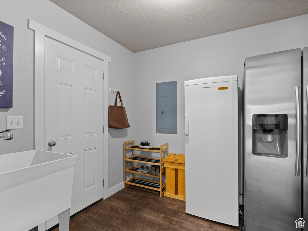Interior space featuring stainless steel refrigerator with ice dispenser, freestanding refrigerator, electric panel, wood finished floors, and a sink