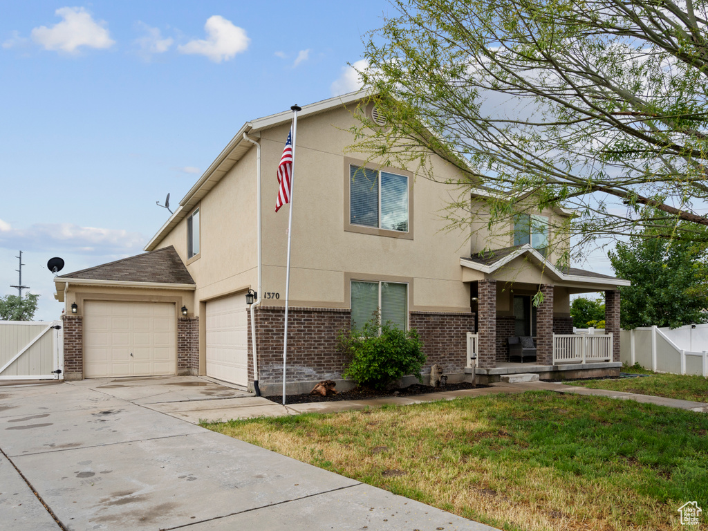 View of front of property featuring a porch, driveway, brick siding, stucco siding, and a gate
