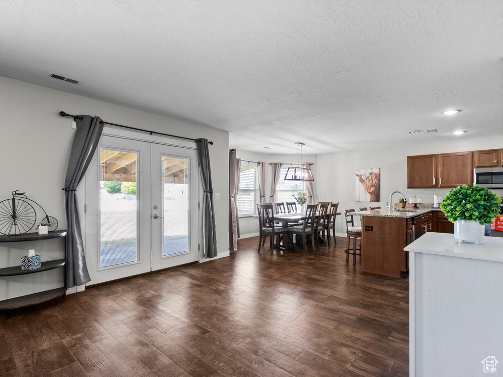 Dining area with french doors, dark wood-style flooring, a textured ceiling, baseboards, and recessed lighting