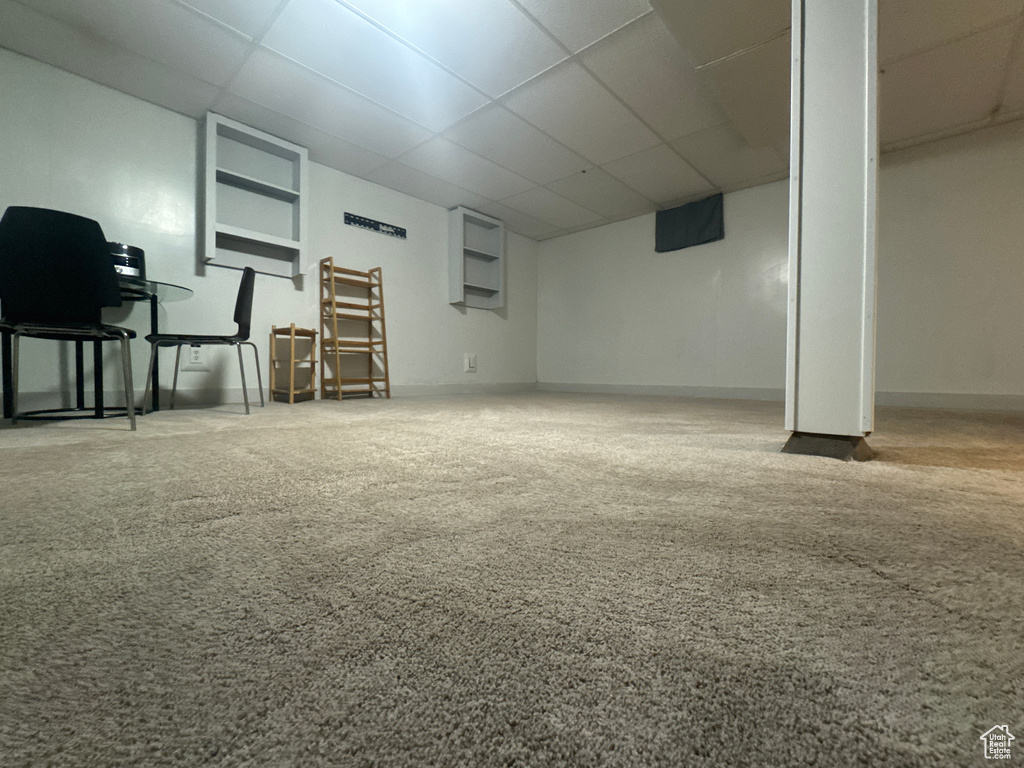 Finished below grade area featuring a paneled ceiling, carpet, and baseboards