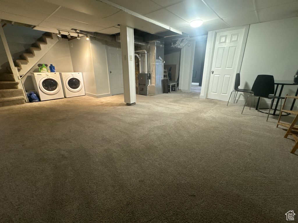 Finished below grade area featuring washing machine and dryer, stairway, carpet floors, and heating unit
