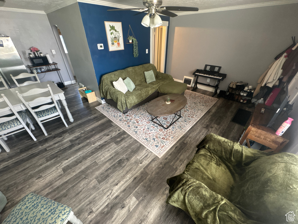 Living area featuring crown molding, wood finished floors, a ceiling fan, and baseboards