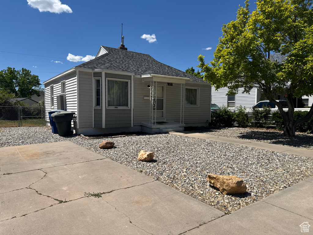 Bungalow-style home featuring roof with shingles and fence