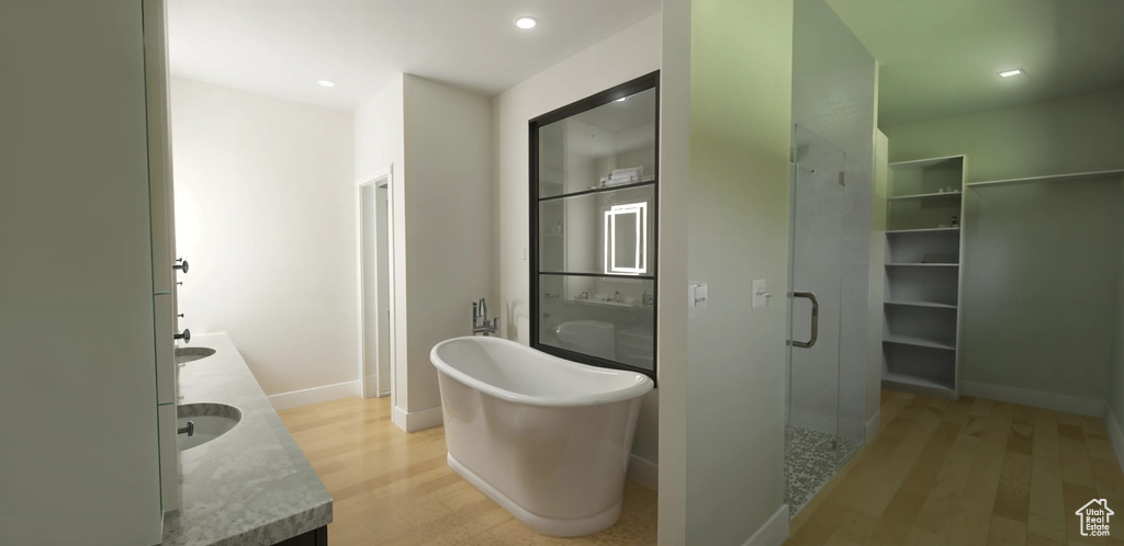 Bathroom with wood finished floors, double vanity, baseboards, and recessed lighting