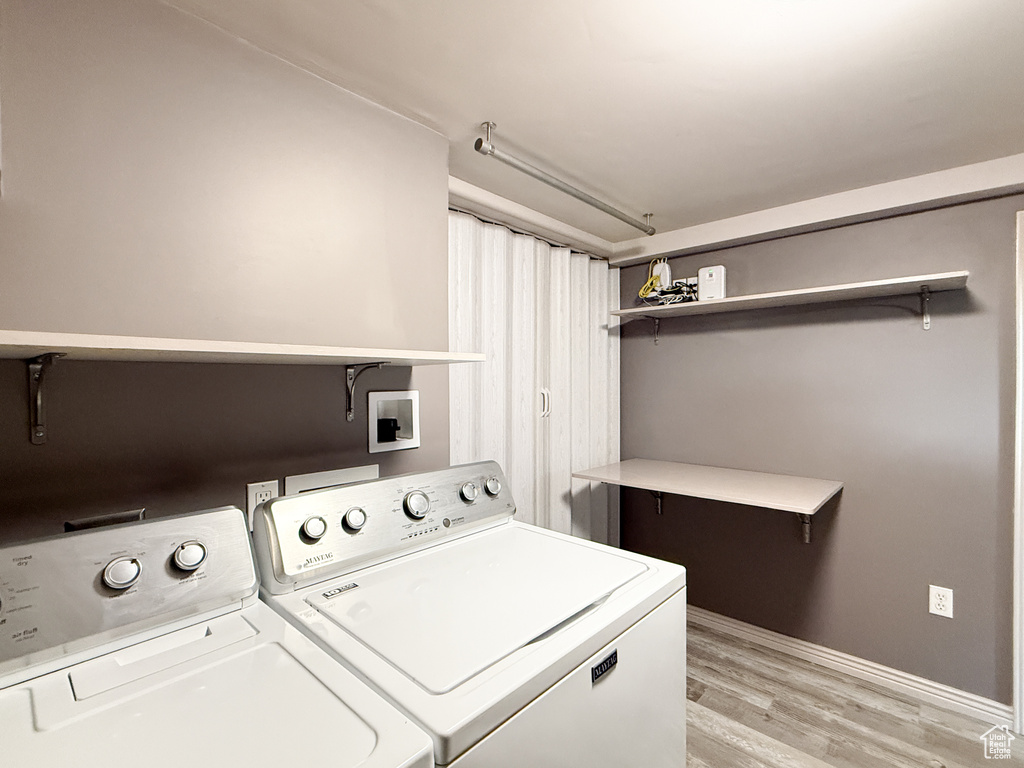 Laundry area with separate washer and dryer, light wood-style flooring, and baseboards