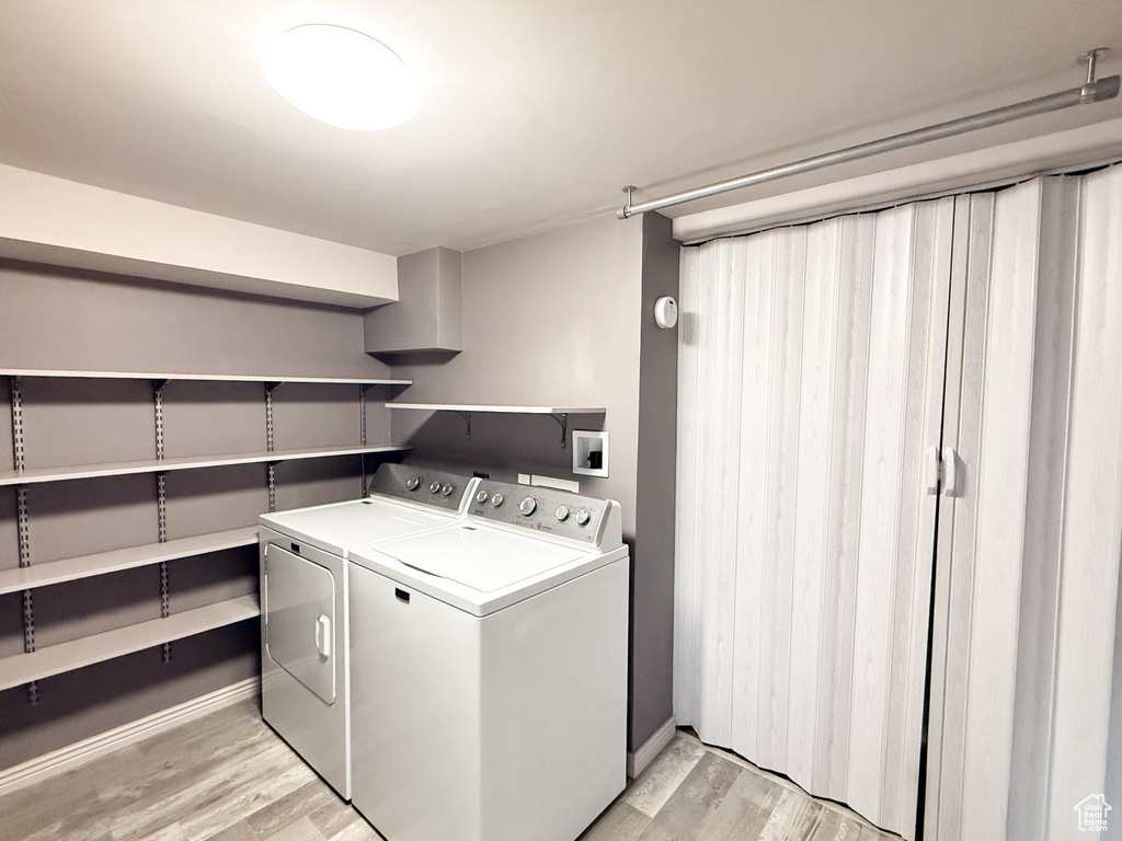 Laundry area featuring washing machine and clothes dryer, light wood-type flooring, and baseboards