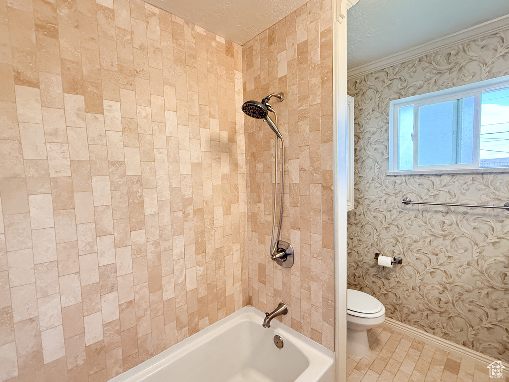 Full bath featuring toilet, bathtub / shower combination, baseboards, and crown molding
