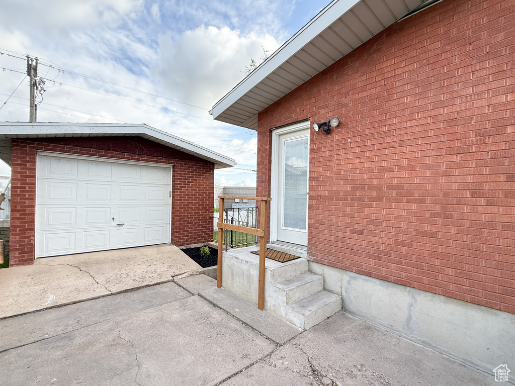 View of property exterior featuring an outbuilding, concrete driveway, brick siding, and a garage