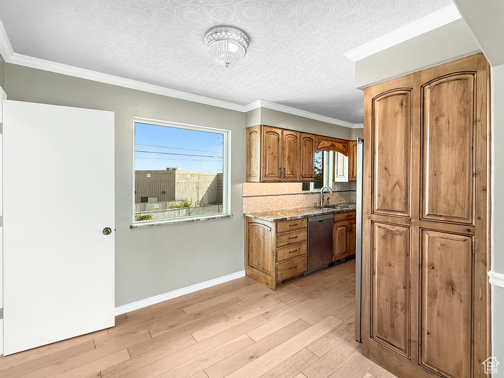 Kitchen featuring dishwasher, light wood-type flooring, brown cabinets, baseboards, and ornamental molding