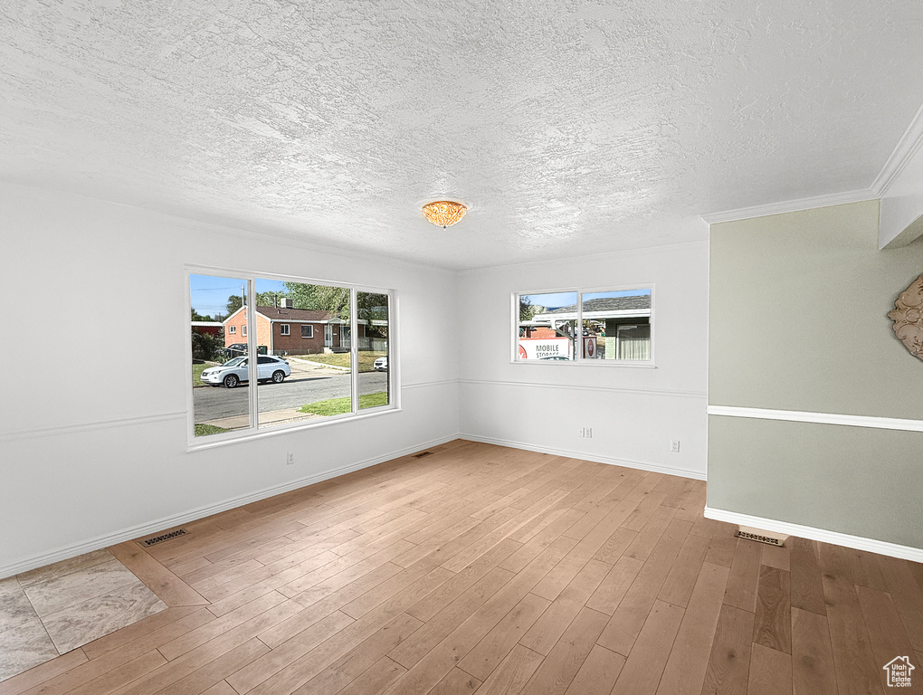 Unfurnished room featuring a textured ceiling, baseboards, and wood finished floors