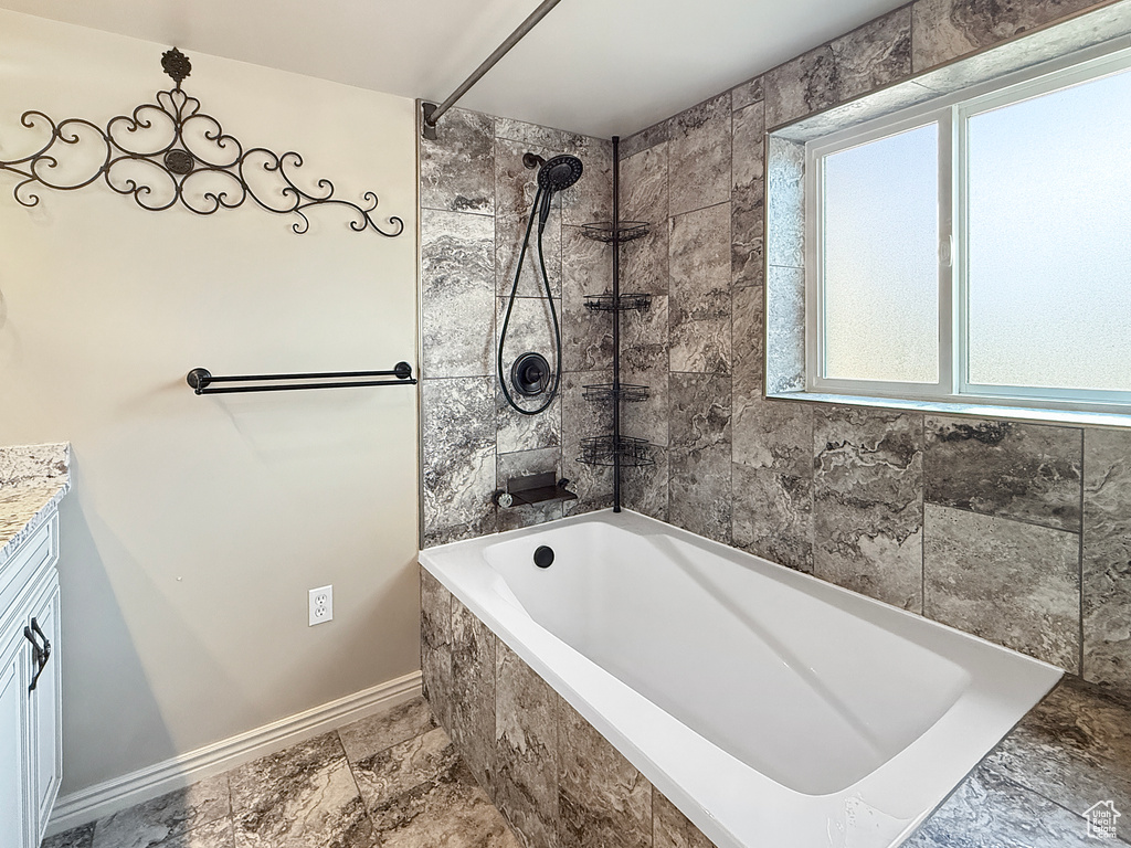 Bathroom with baseboards, vanity, and bathtub / shower combination