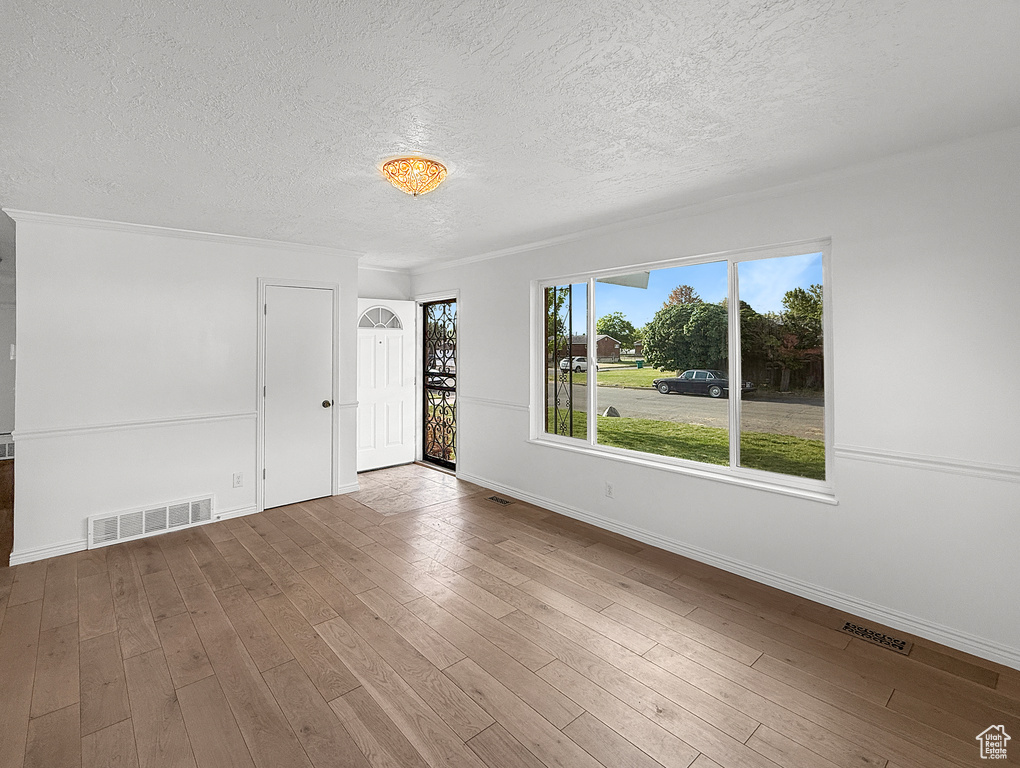 Empty room with a textured ceiling, baseboards, and wood finished floors