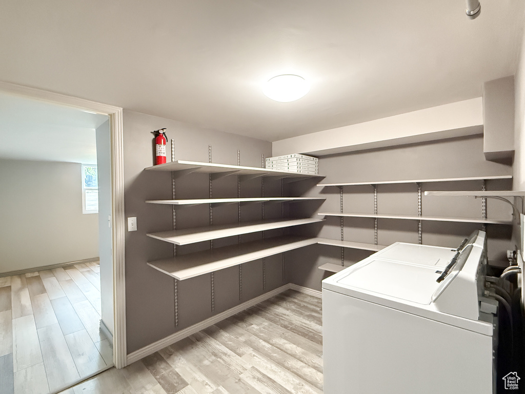 Laundry room featuring washer and dryer, light wood-type flooring, and baseboards
