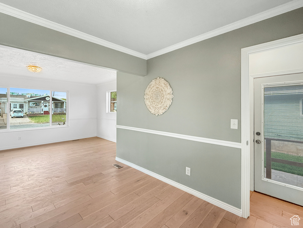 Unfurnished room featuring baseboards, light wood finished floors, and crown molding