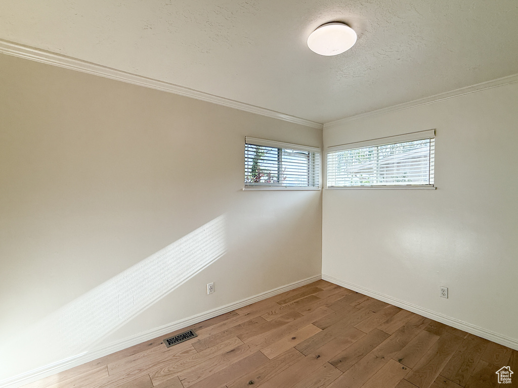 Spare room with baseboards, wood finished floors, and crown molding