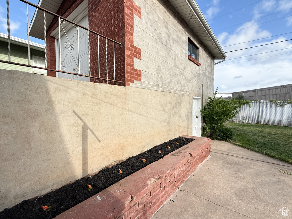 View of side of home with fence, brick siding, and stucco siding