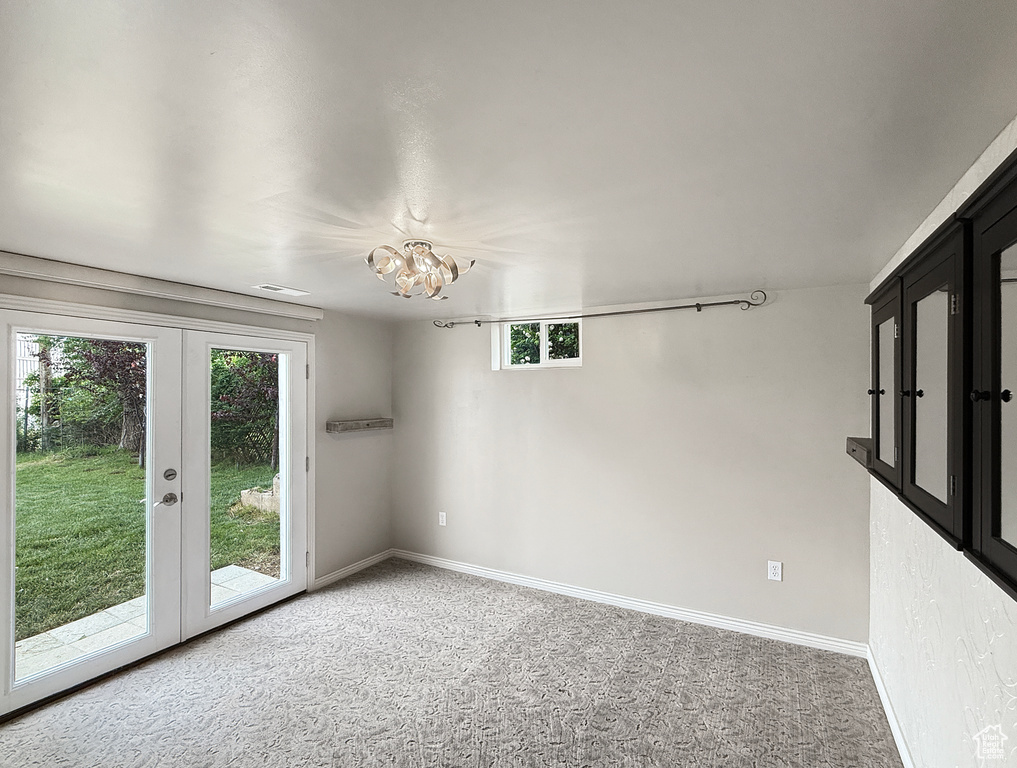 Unfurnished room with light colored carpet, french doors, baseboards, and a chandelier