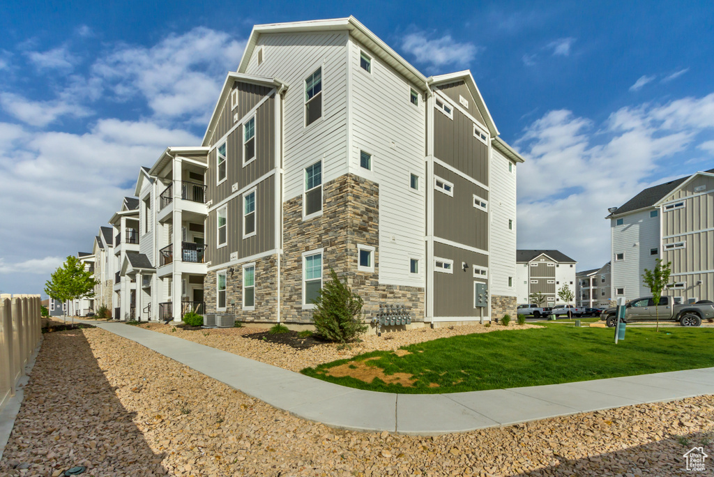 View of building exterior featuring fence, a residential view, and central air condition unit