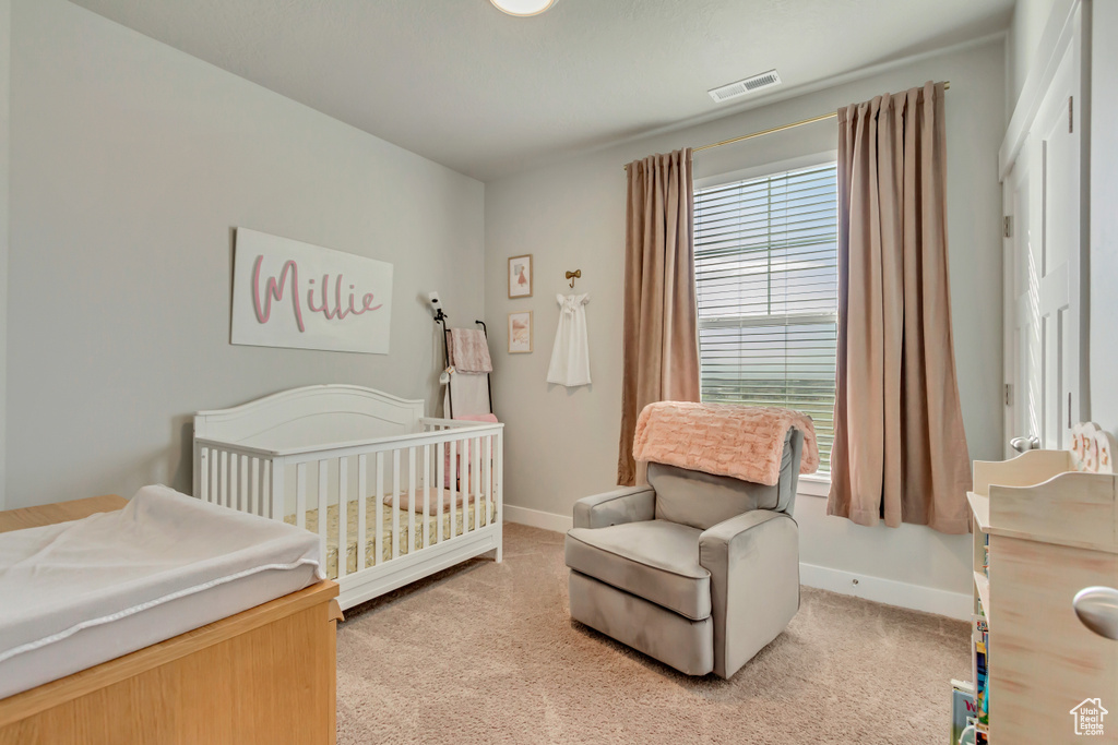 Bedroom with light colored carpet, baseboards, and a nursery area