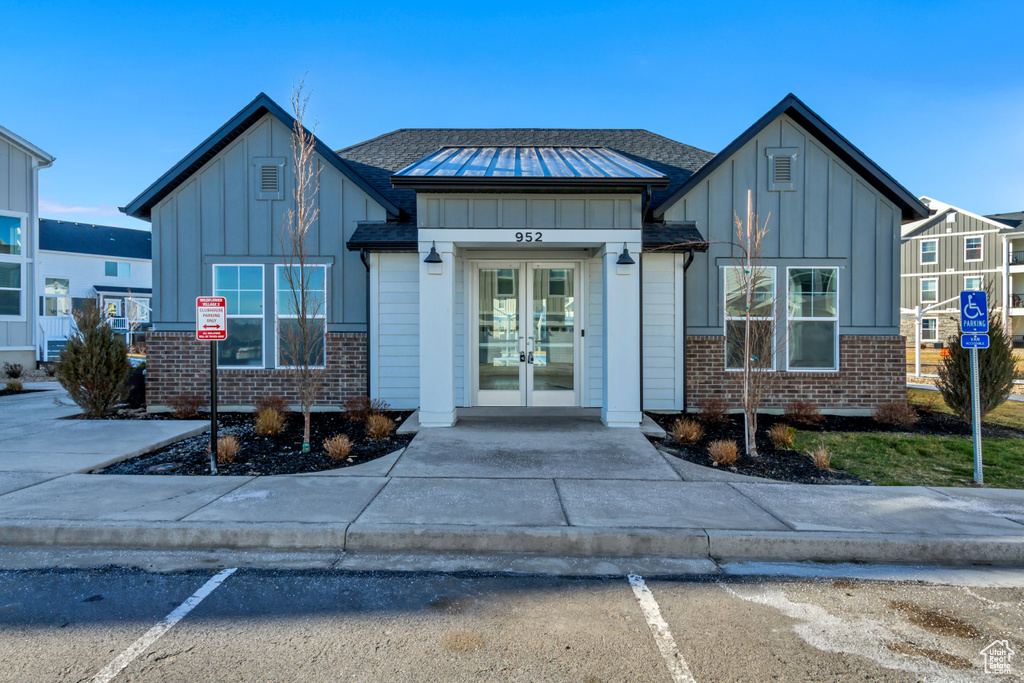 View of front of home featuring board and batten siding, french doors, and brick siding