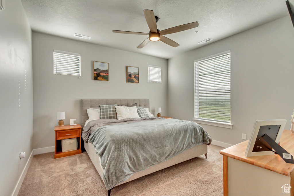 Bedroom with baseboards, light carpet, and a ceiling fan