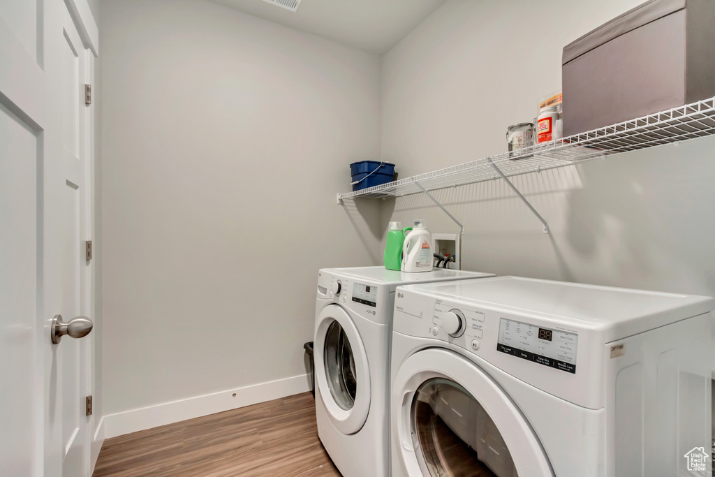 Laundry area featuring baseboards, washing machine and clothes dryer, and light wood-style floors